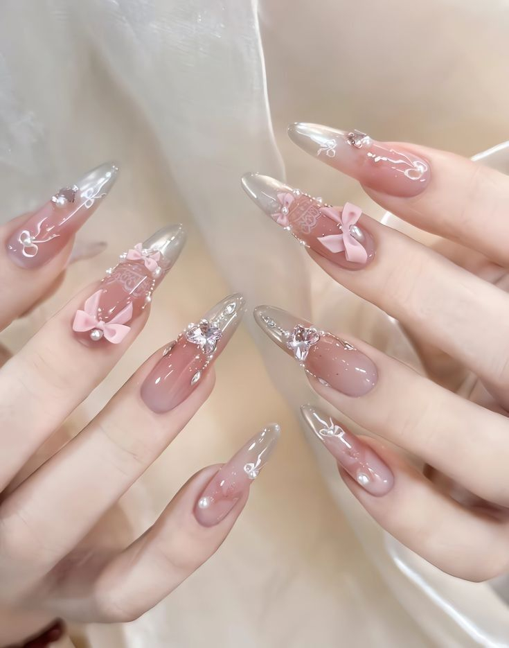 Almond sheer pink and shimmery nude nails with delicate silver bow charms