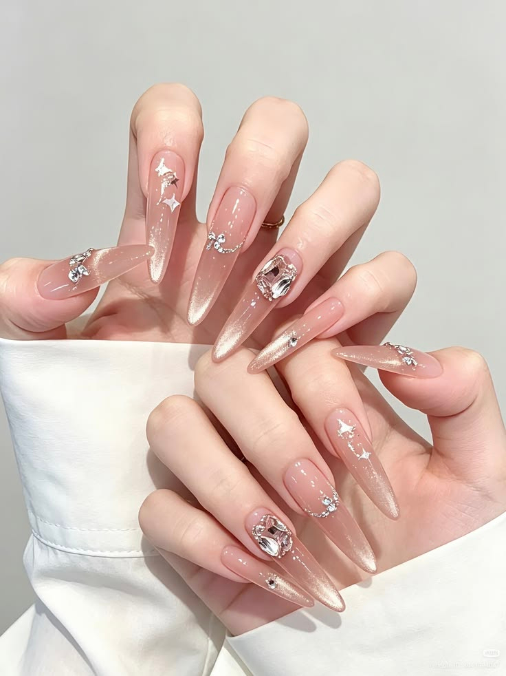 Long stiletto nude cat eye nails with large diamond gemstones and star glitter
